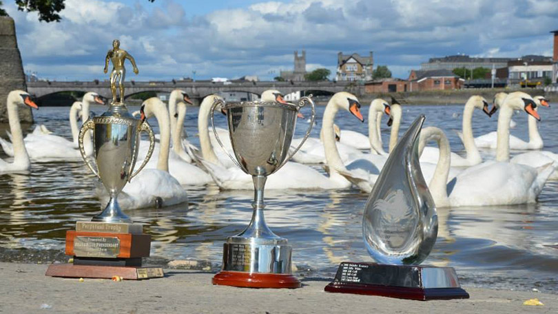 Three trophies on the slipway to a river, swans behind and castle and bridge in background