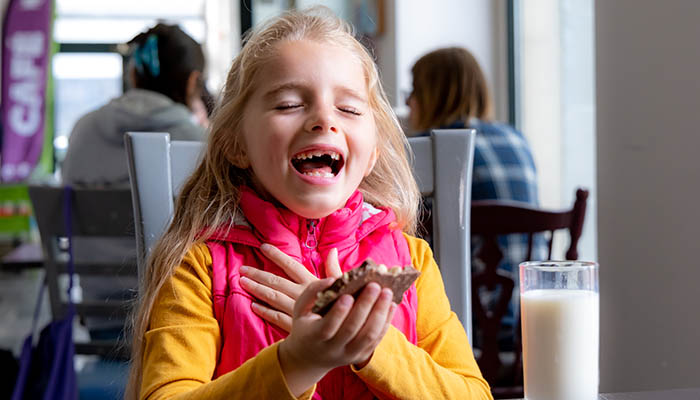 Young girl laughing eating a cookie. Photo: Paul Corey